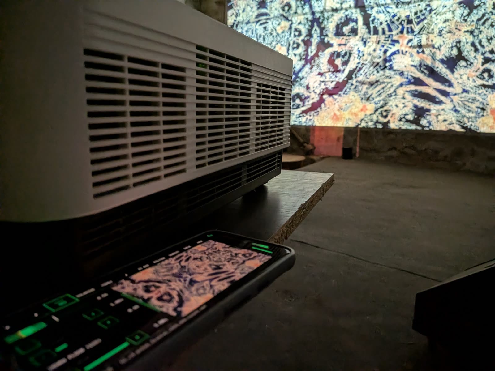 Phone running PVJ beside a projector, the same pattern filling the wall behind